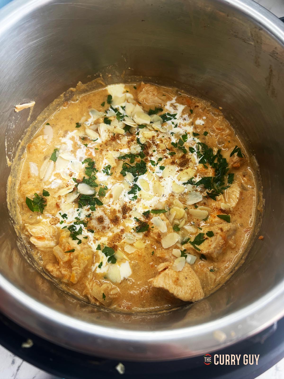 Chicken korma garnished with garam masala and almonds in the slow cooker