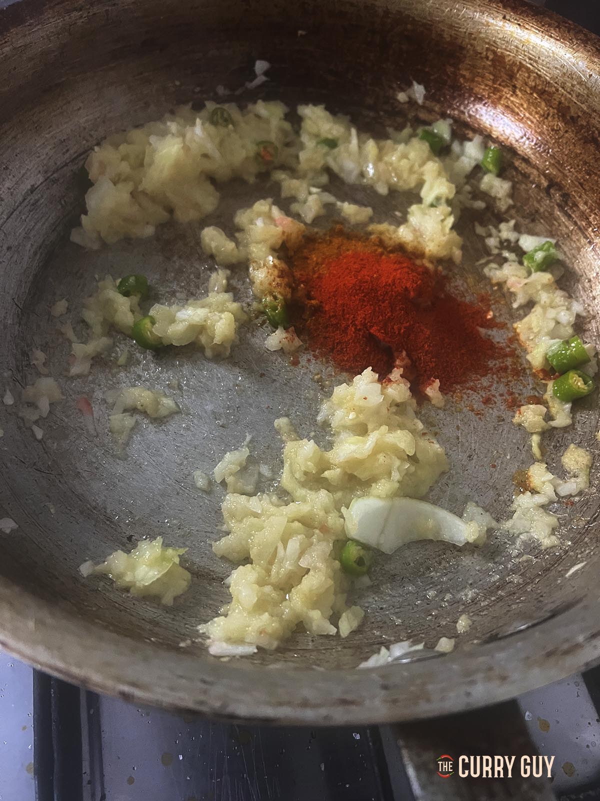 Stirring in the chillies, chopped onions, mixed powder and chilli powder.