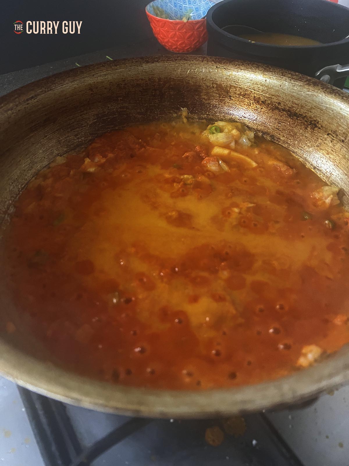 Adding more base curry sauce to the pan.