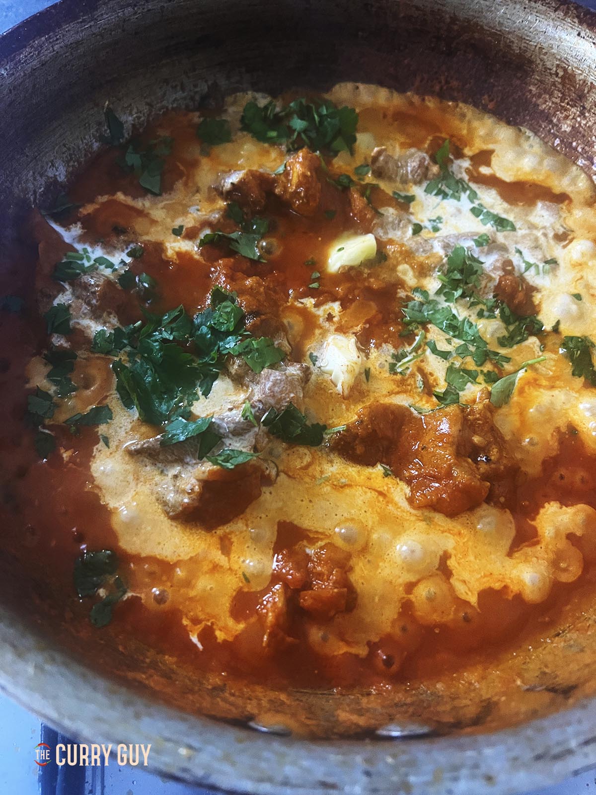 Adding cream, butter and coriander (cilantro) to the pan.
