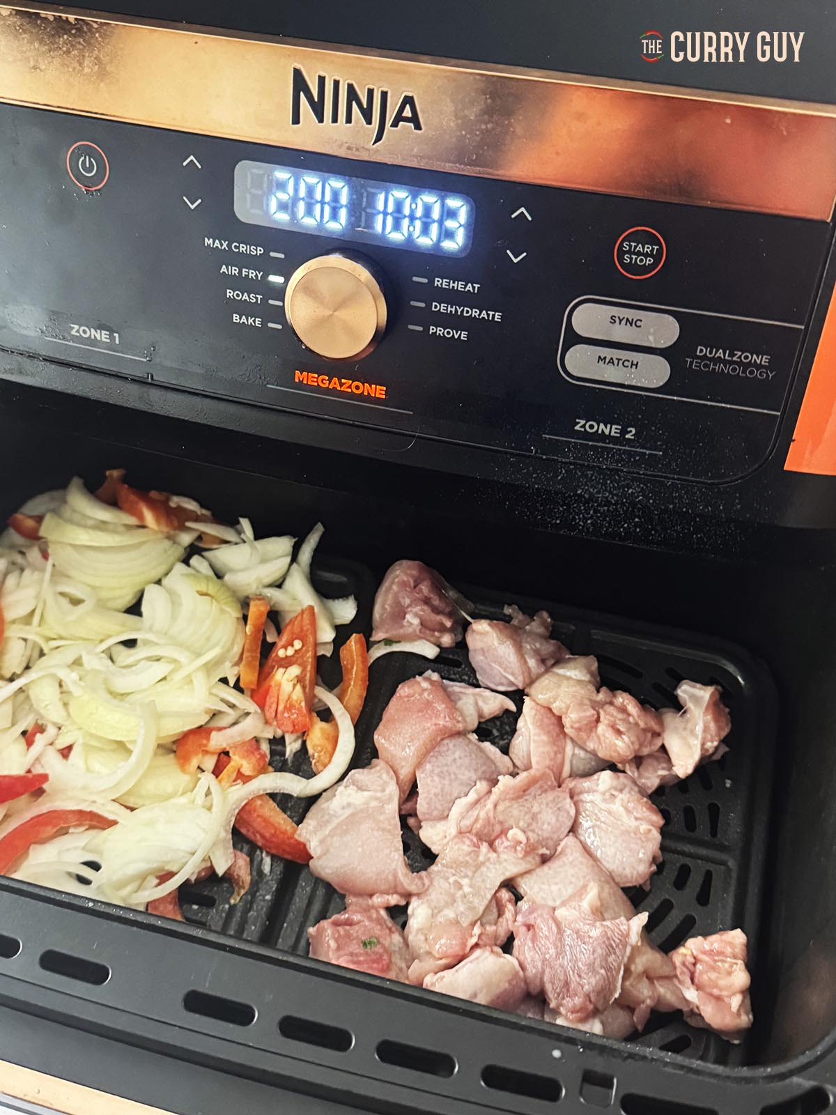 Onions, pepper and chicken ready for air frying in the cooking basket.
