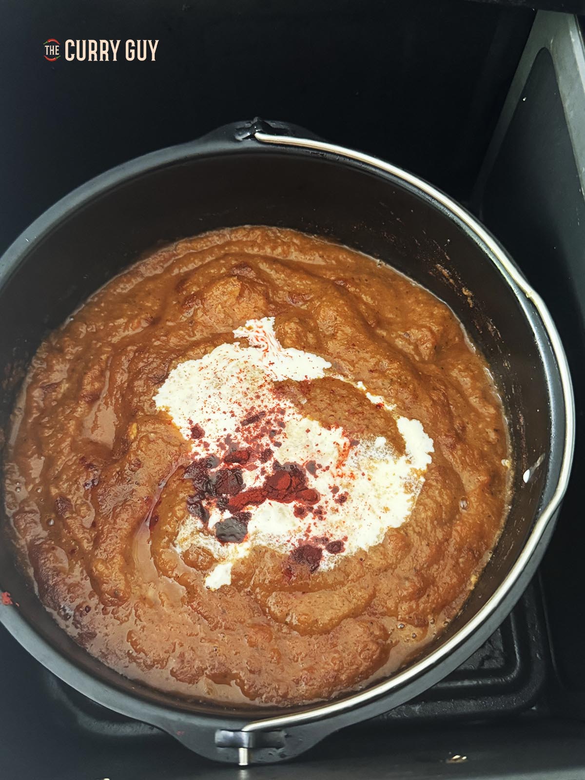 Adding the cream, garam masala and red food colouring to the sauce.