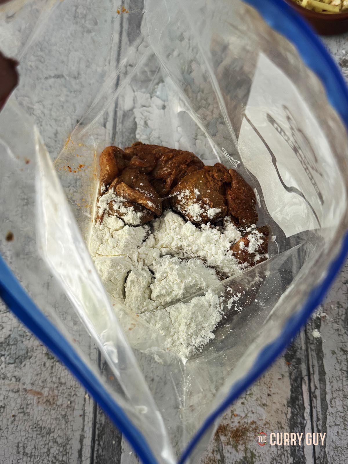 The marinated meat in a bag with the flours ready to be shaken and coated with the flours.