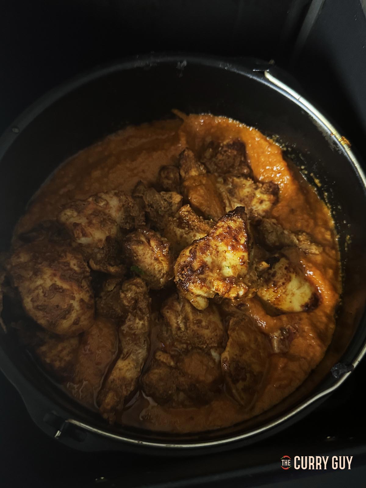 Adding the cooked chicken to the pathia sauce.