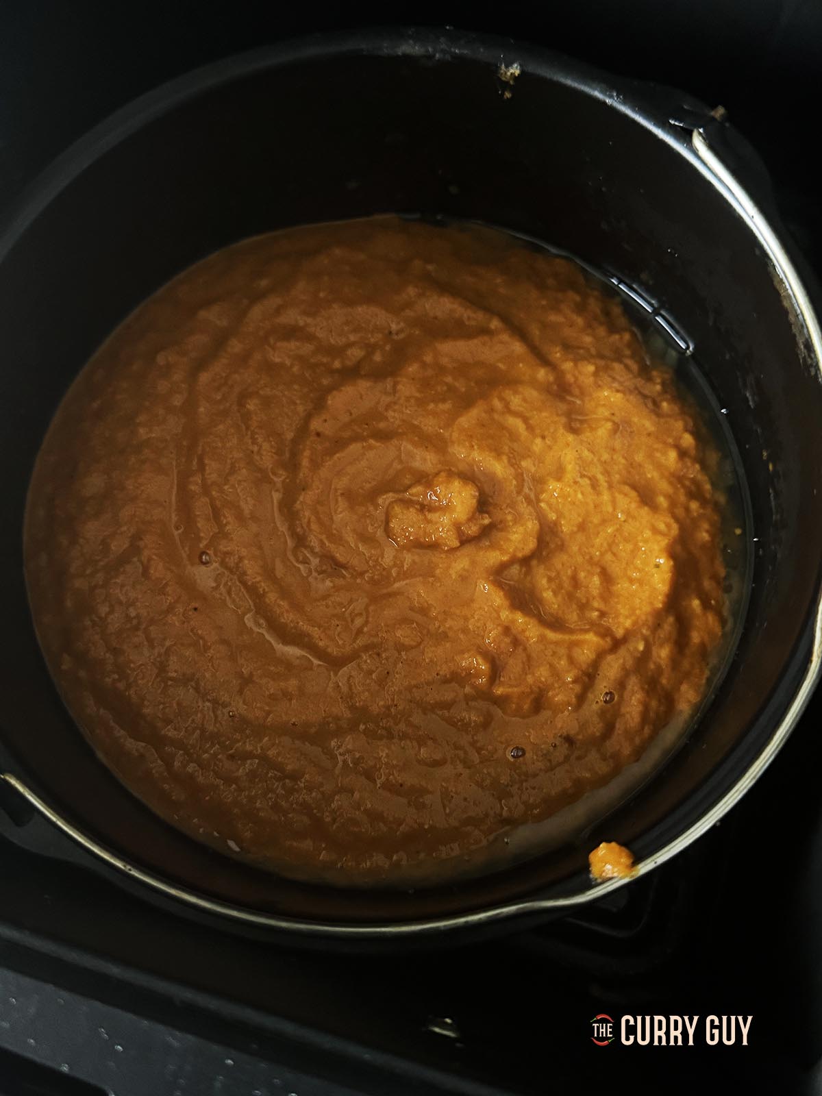 Adding the prepared pathia sauce to the pan with the fried onions.