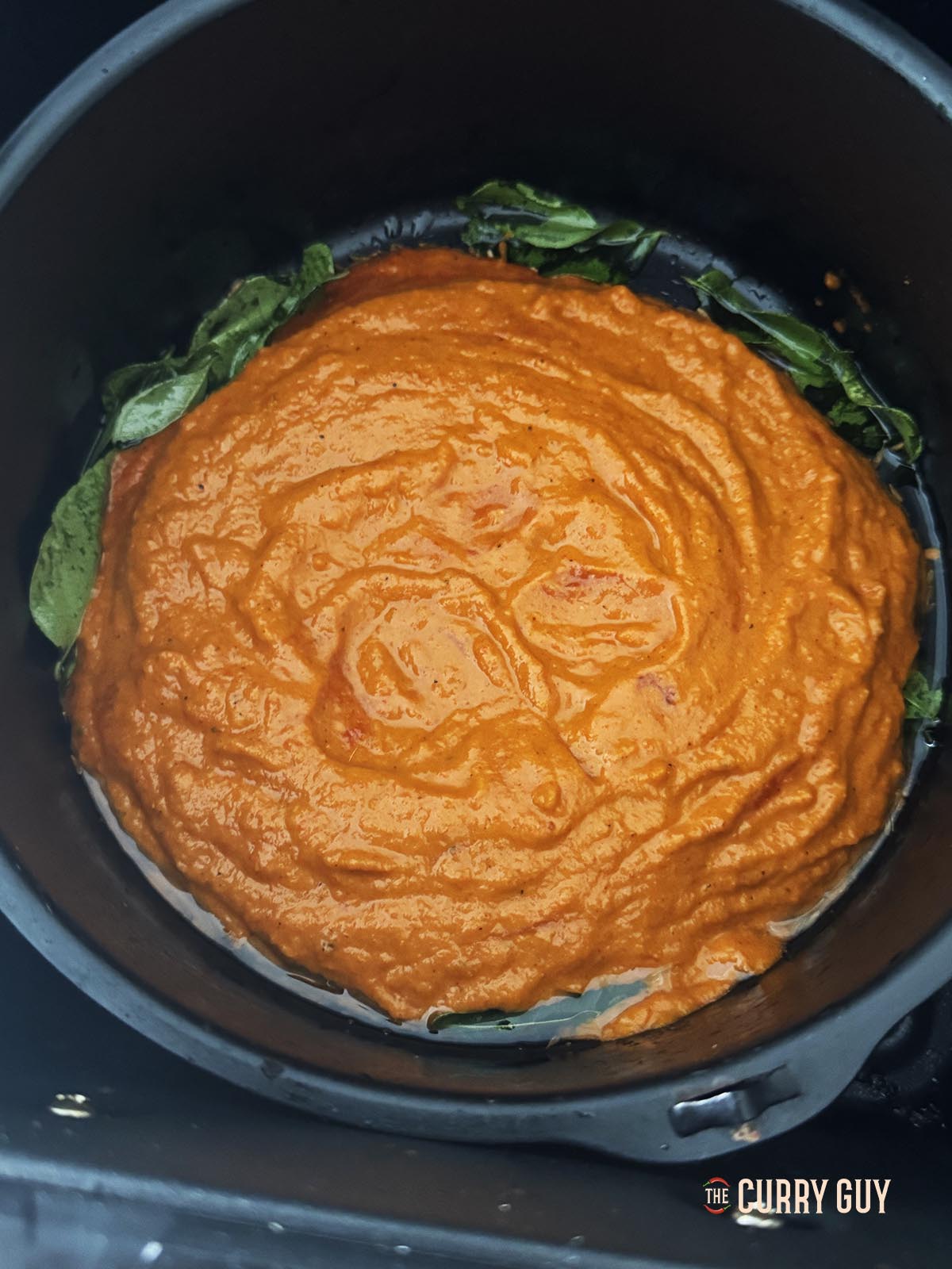 Adding the blended curry sauce to the curry leaves and cumin in the pan.