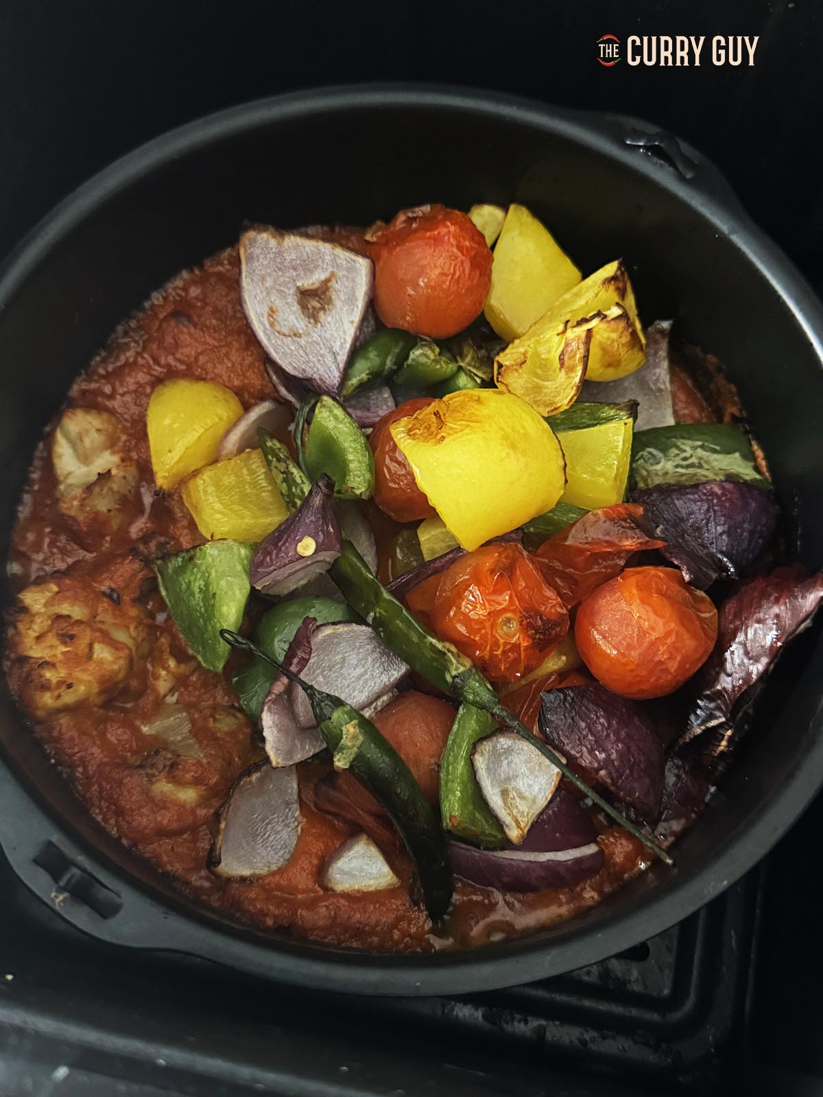 Adding the roasted vegetables to the pan.