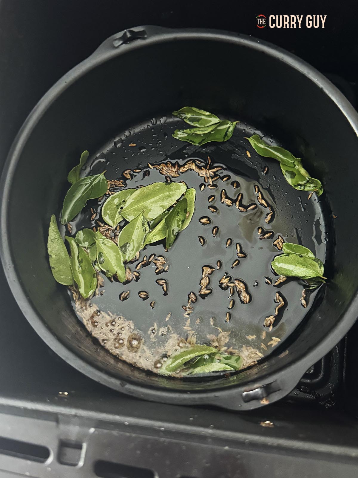 Infusing the curry leaves and cumin seeds in oil.
