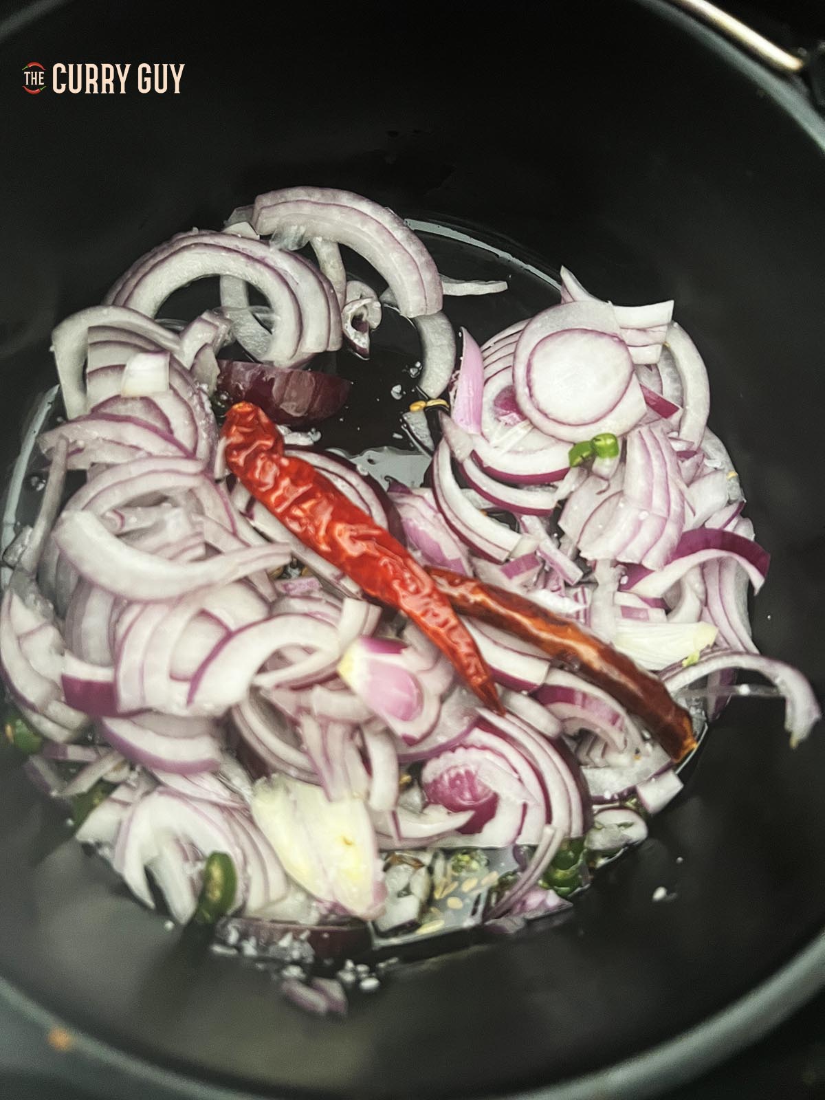 Adding the sliced onion to the oil.