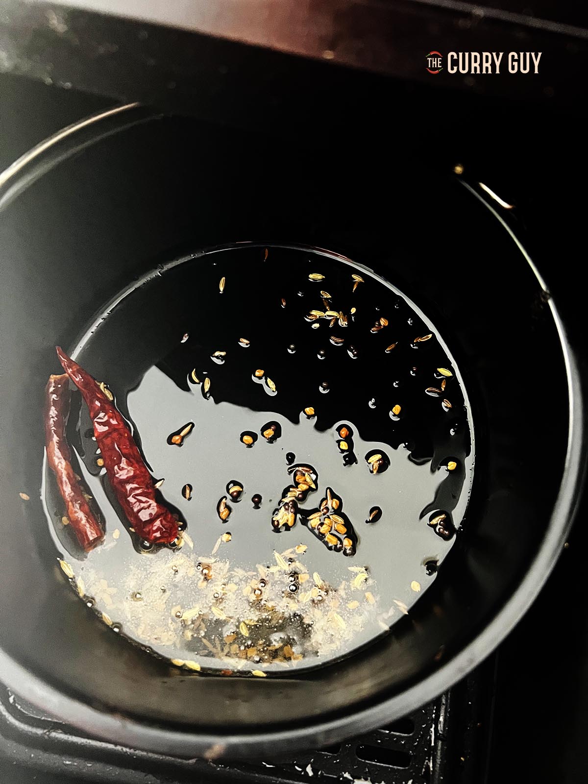 Tempering the whole spices in oil in a pan in the air fryer.