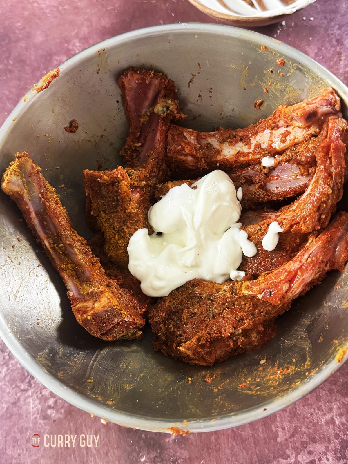 Adding the yoghurt to the smoked lamb chops.