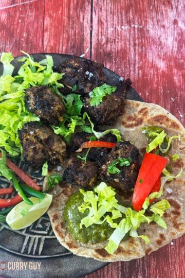The lamb tikka served on flatbread with coriander sauce and salad vegetables.
