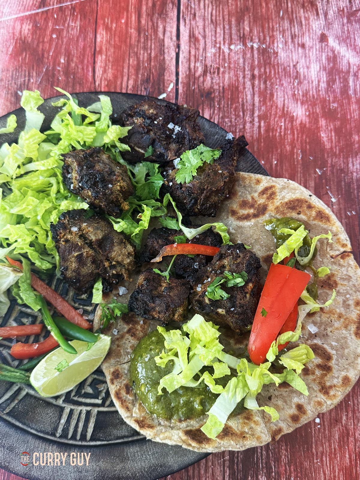 The lamb tikka served on flatbread with coriander sauce and salad vegetables.