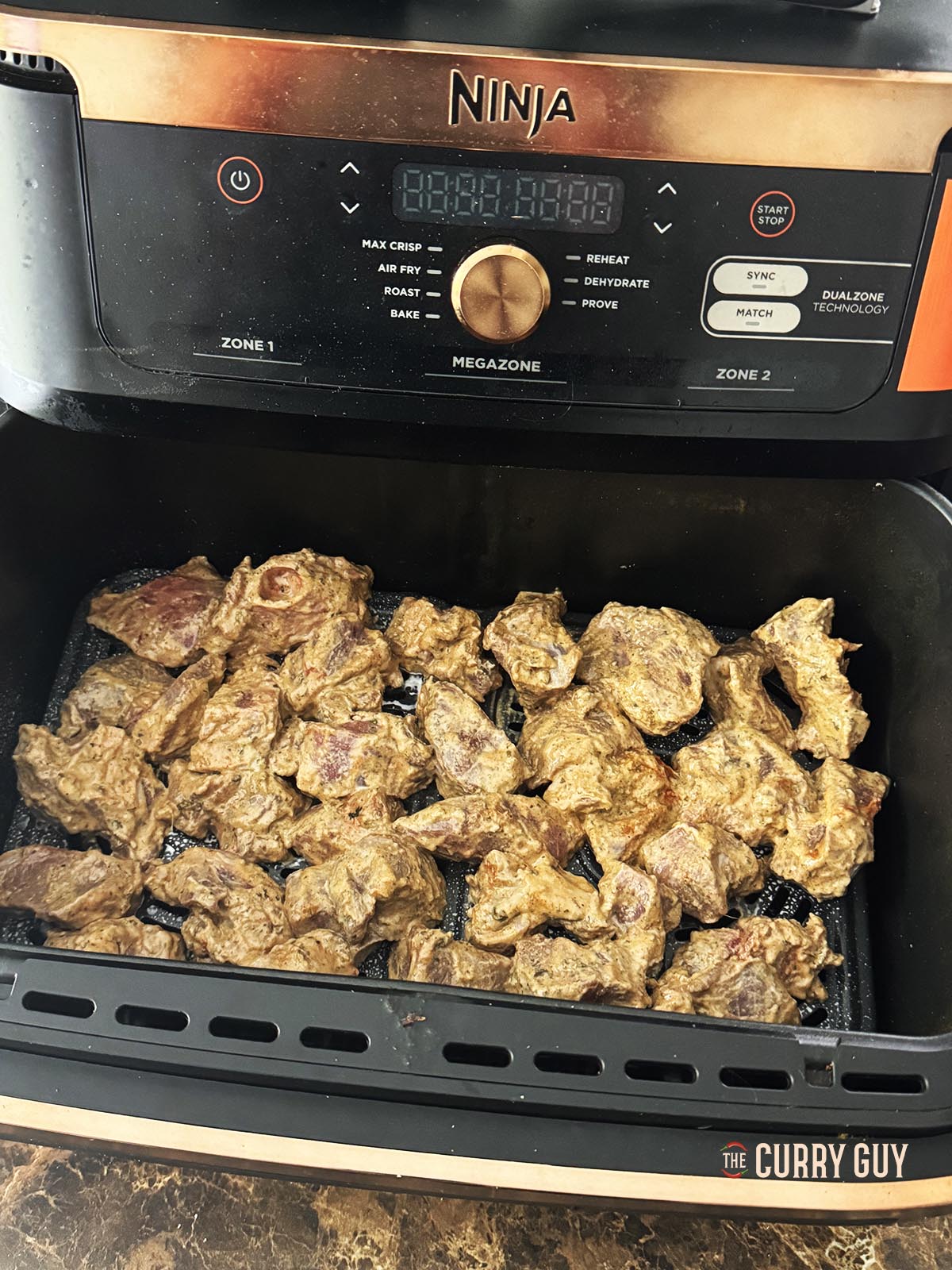 Placing the lamb into the cooking basket of the air fryer.
