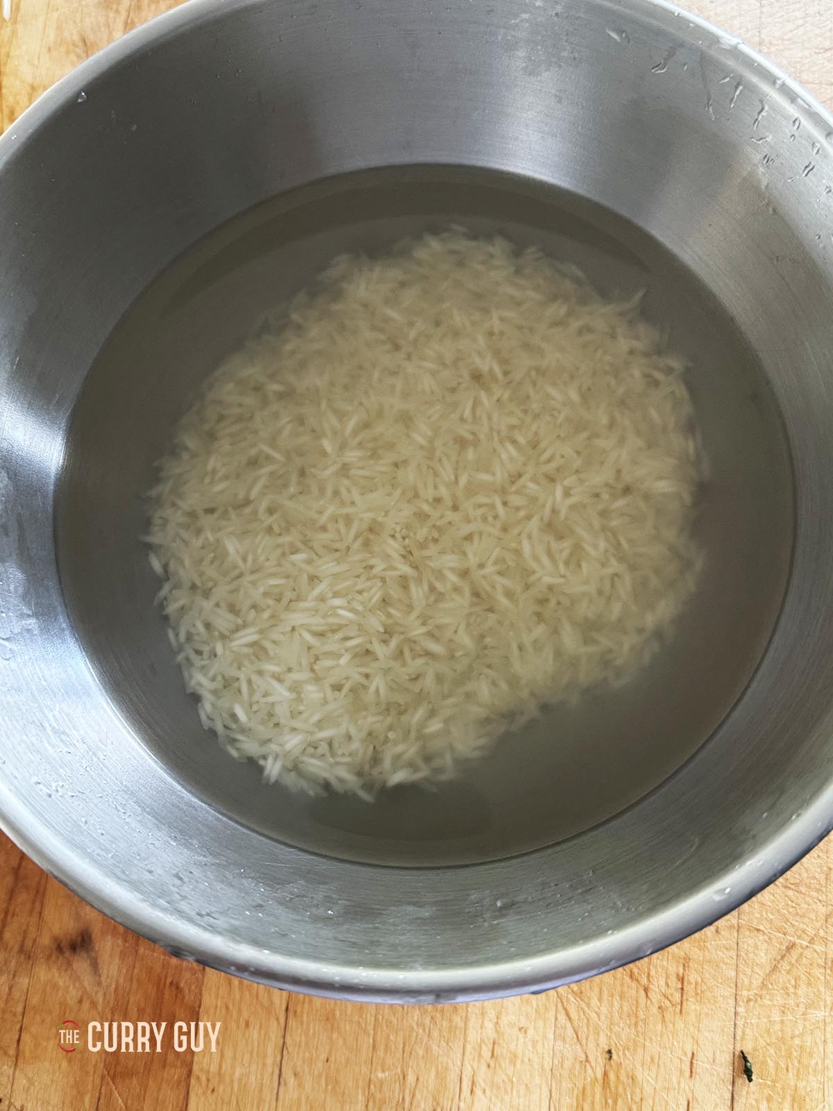 The rice covered with water that is no longer milky as the starch has been removed.