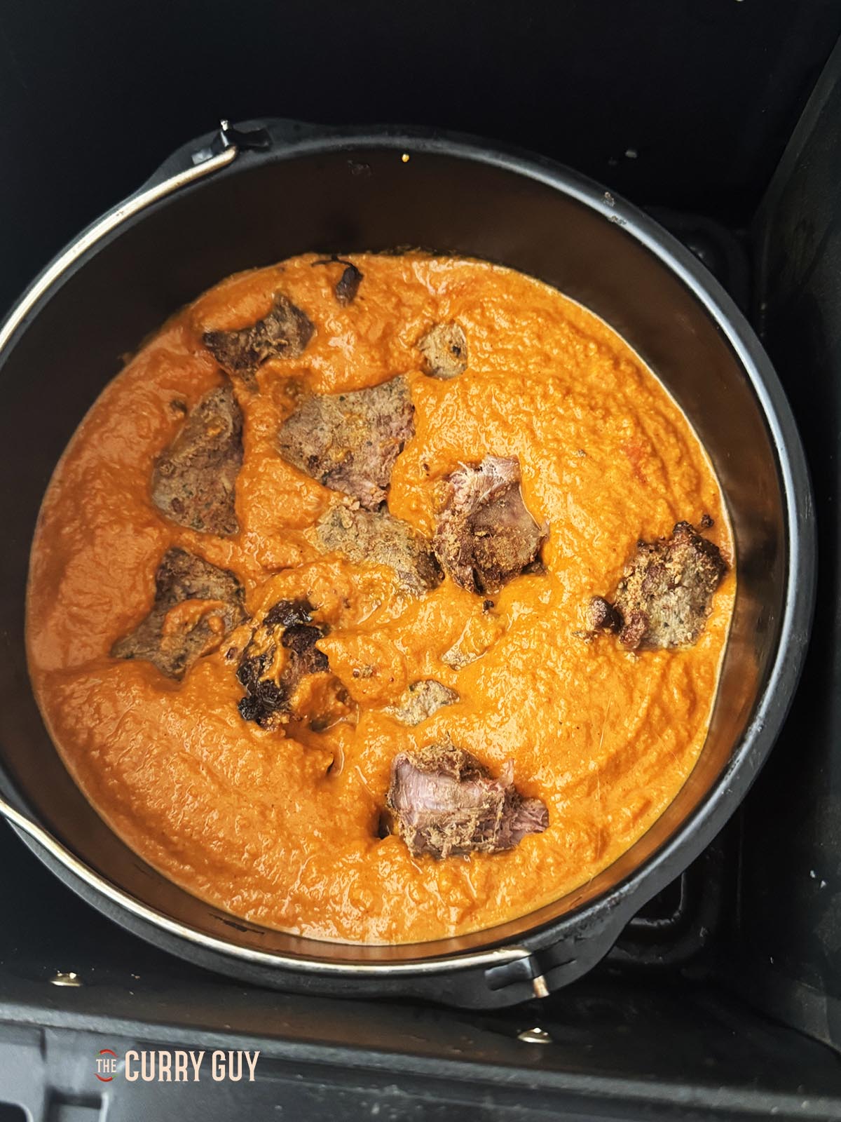 The curry sauce and meat in a cake tin for air frying.