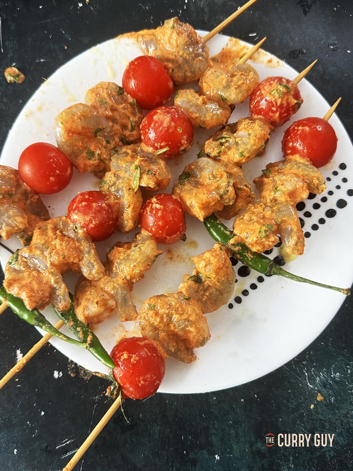 The marinated shrimp, chillies and tomatoes skewered onto wooden skewers.