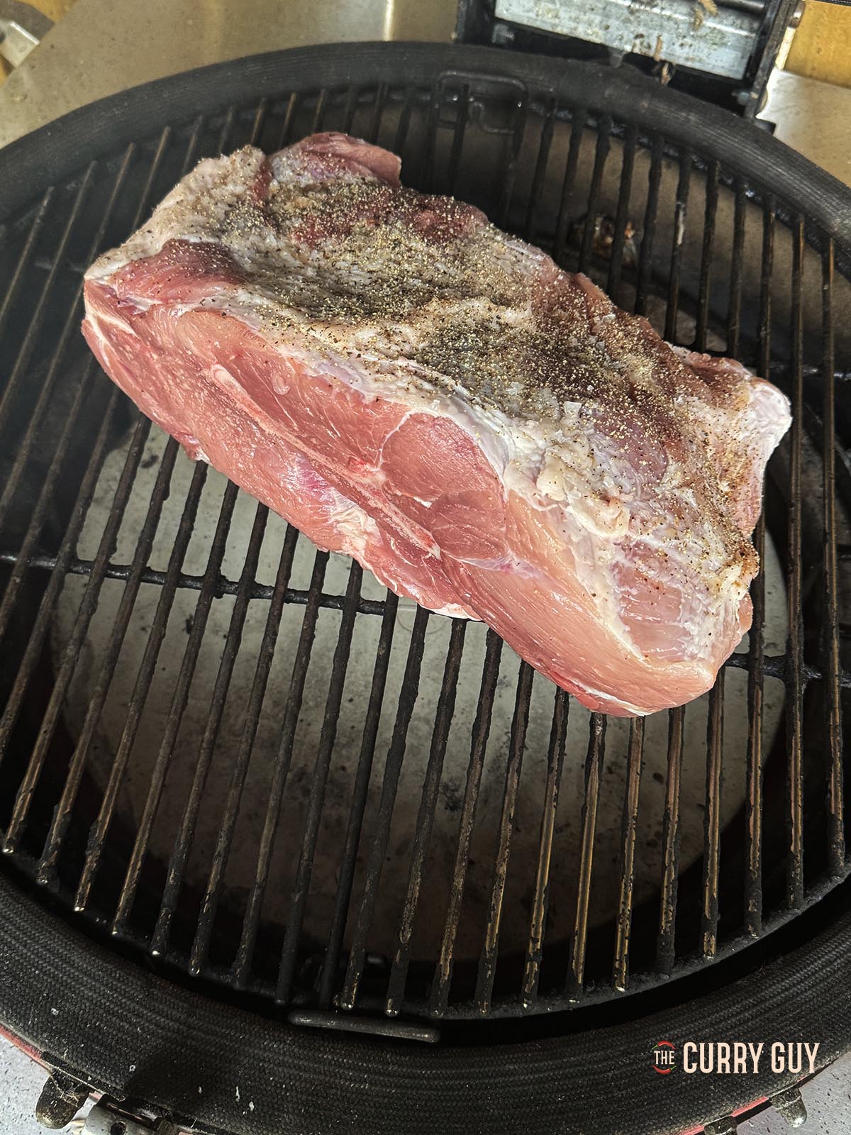 Placing the pork shoulder over an indirect heat on the barbecue.