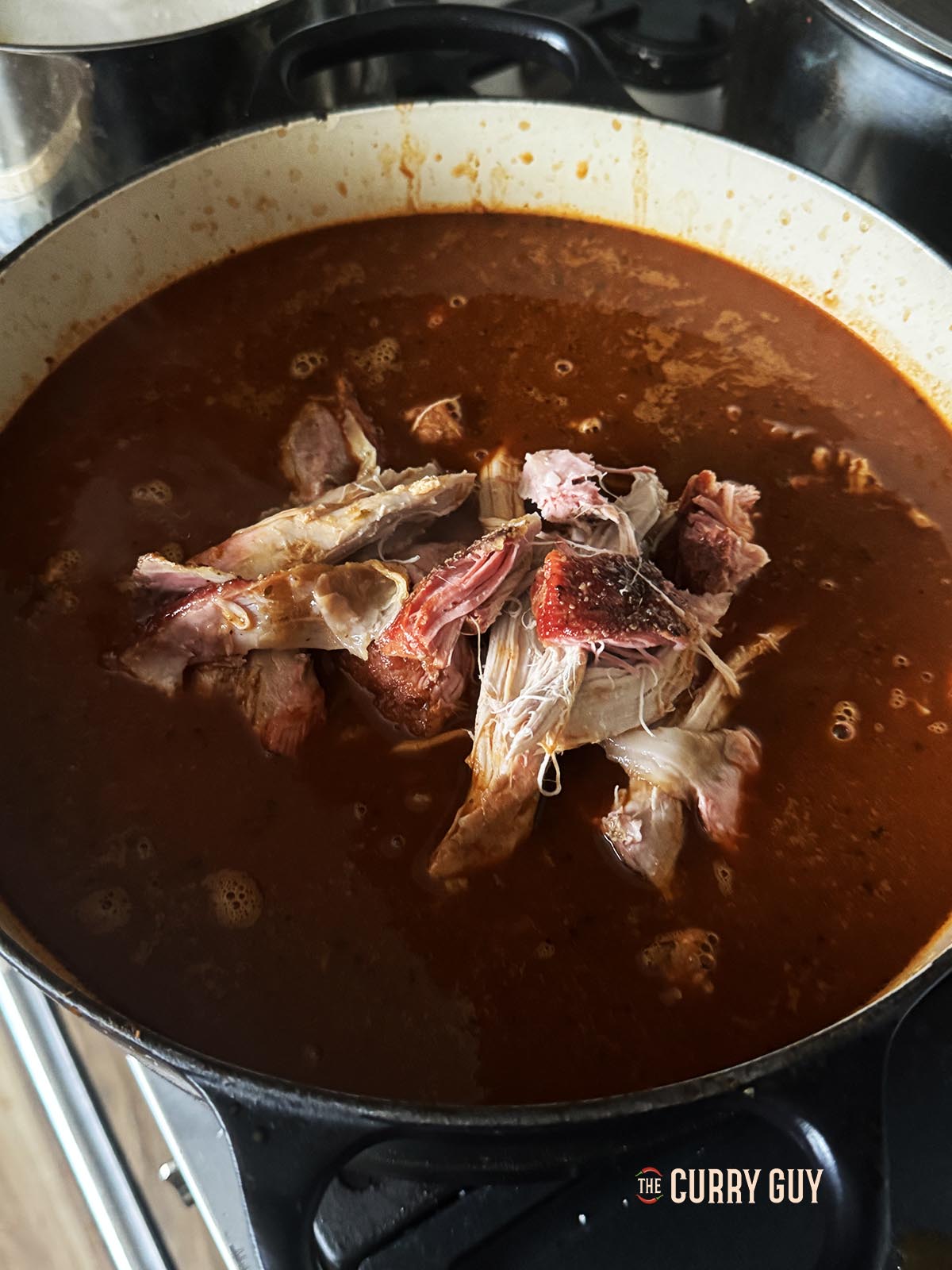 Adding the meat to the pozole broth.
