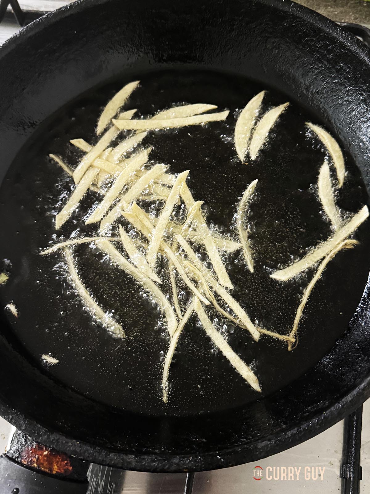 Frying the tortilla strips in oil. 