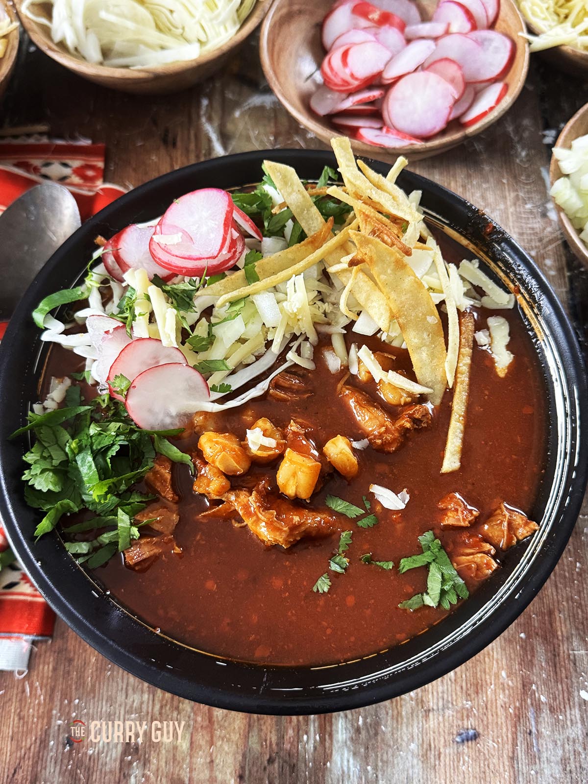 Pozole Rojo served in a dish with garnishes.