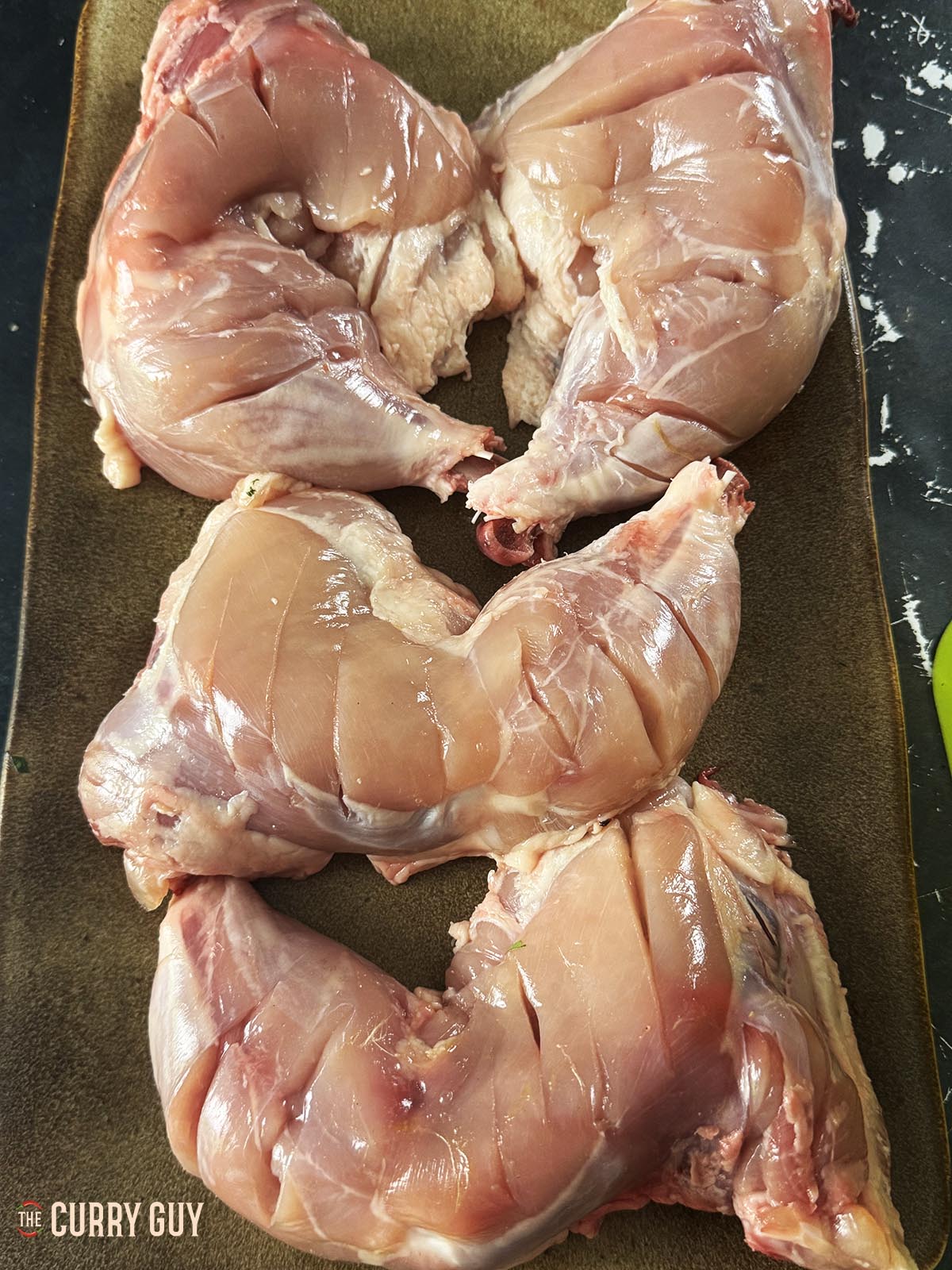 The chicken legs, with skin removed and scored in several places.