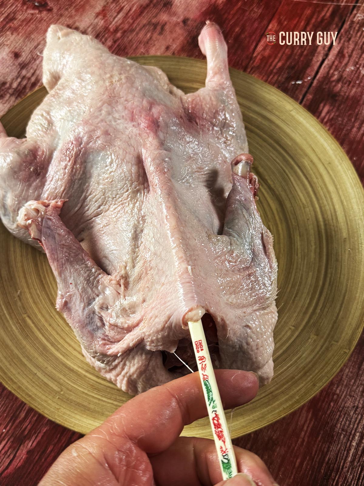 Using a chopstick to separate the skin and meat of the duck in more difficult to reach areas.