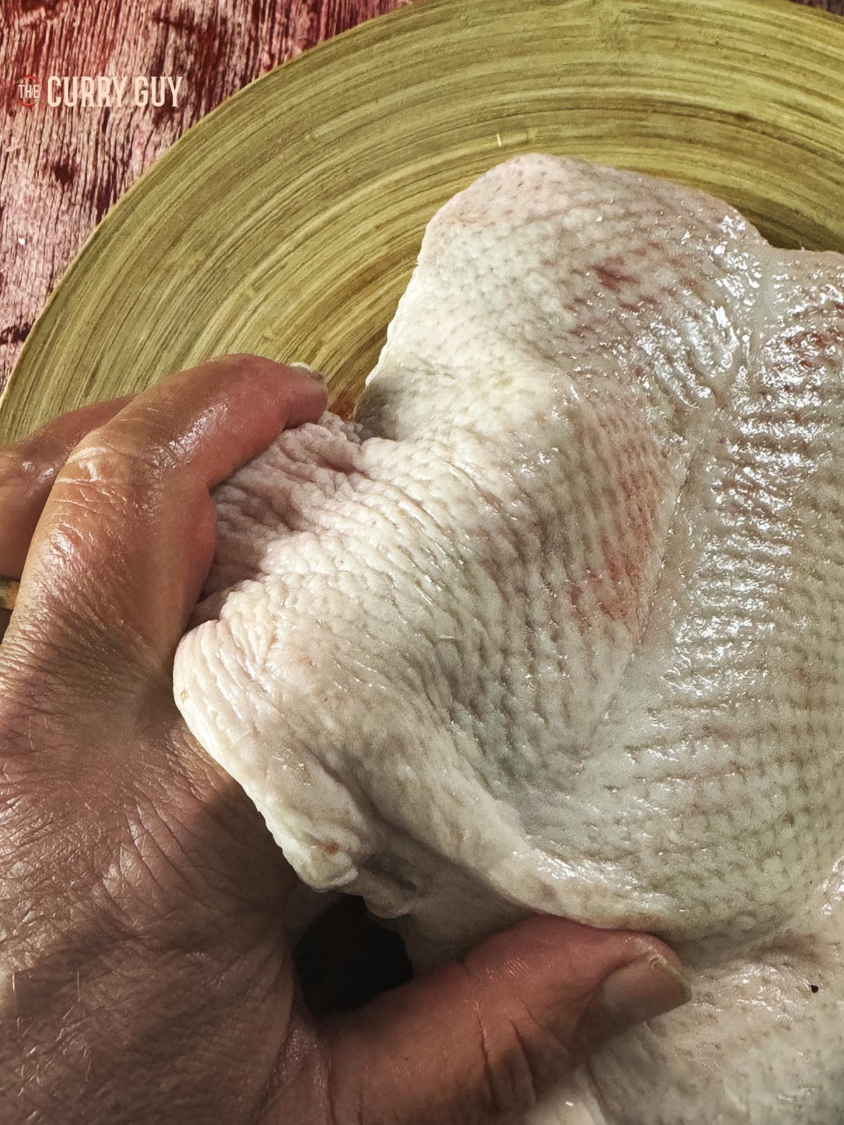 Carefully running a finger between the skin and meat of the duck to separate the skin and meat.