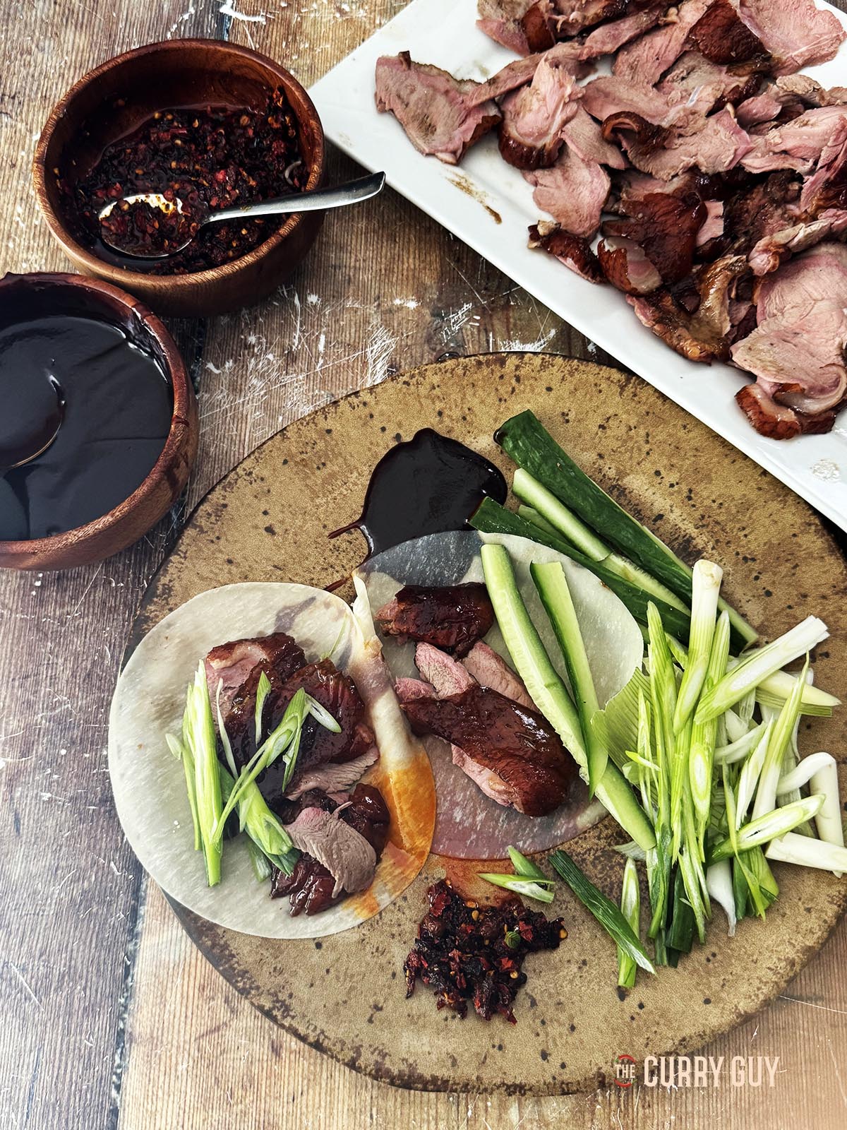 Serving the duck with pancakes, scallions, hoisin and cucumber slices.