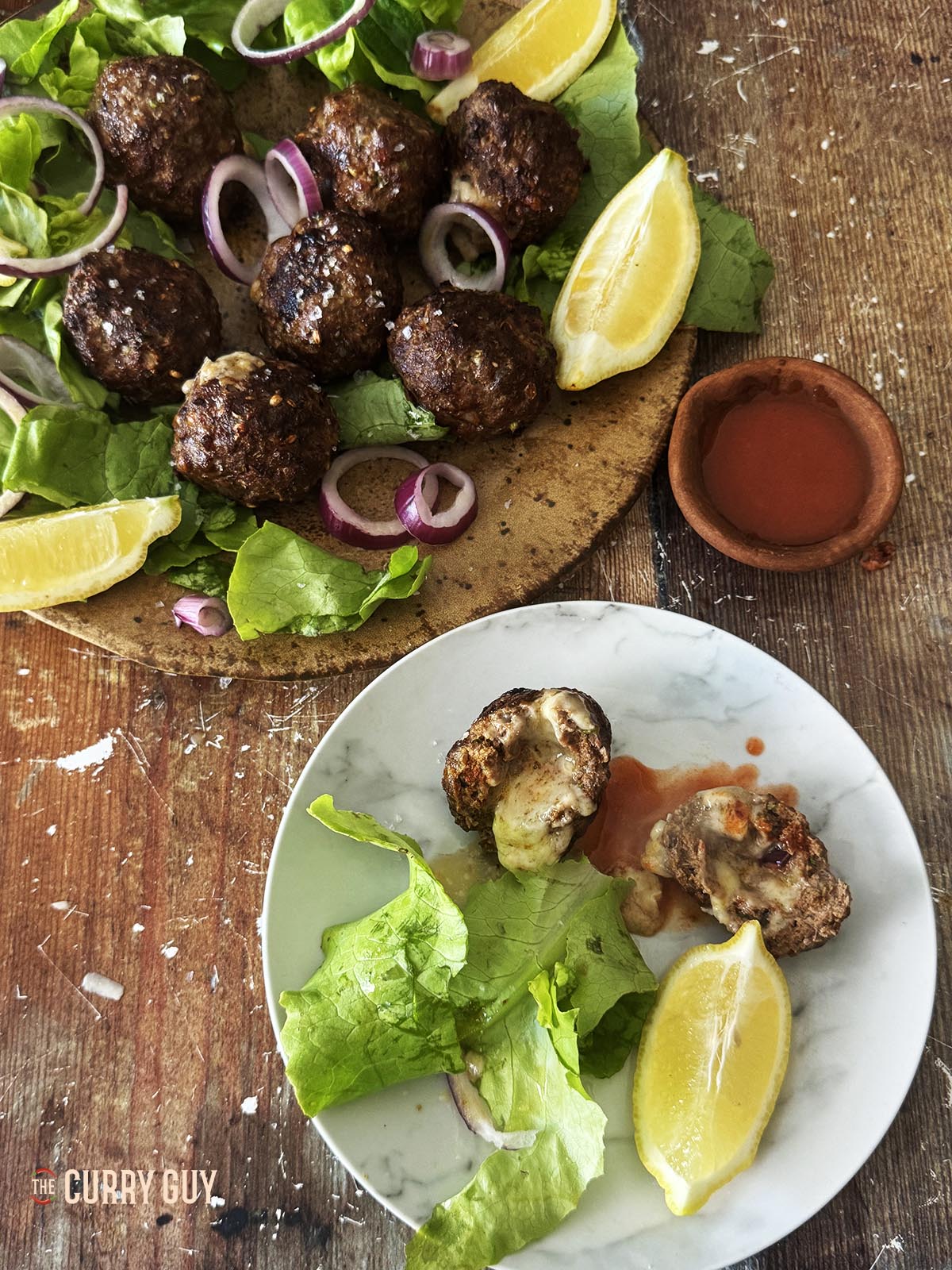 The koftas on a serving plate with an individual plate with an open kofta displaying the melted cheese.