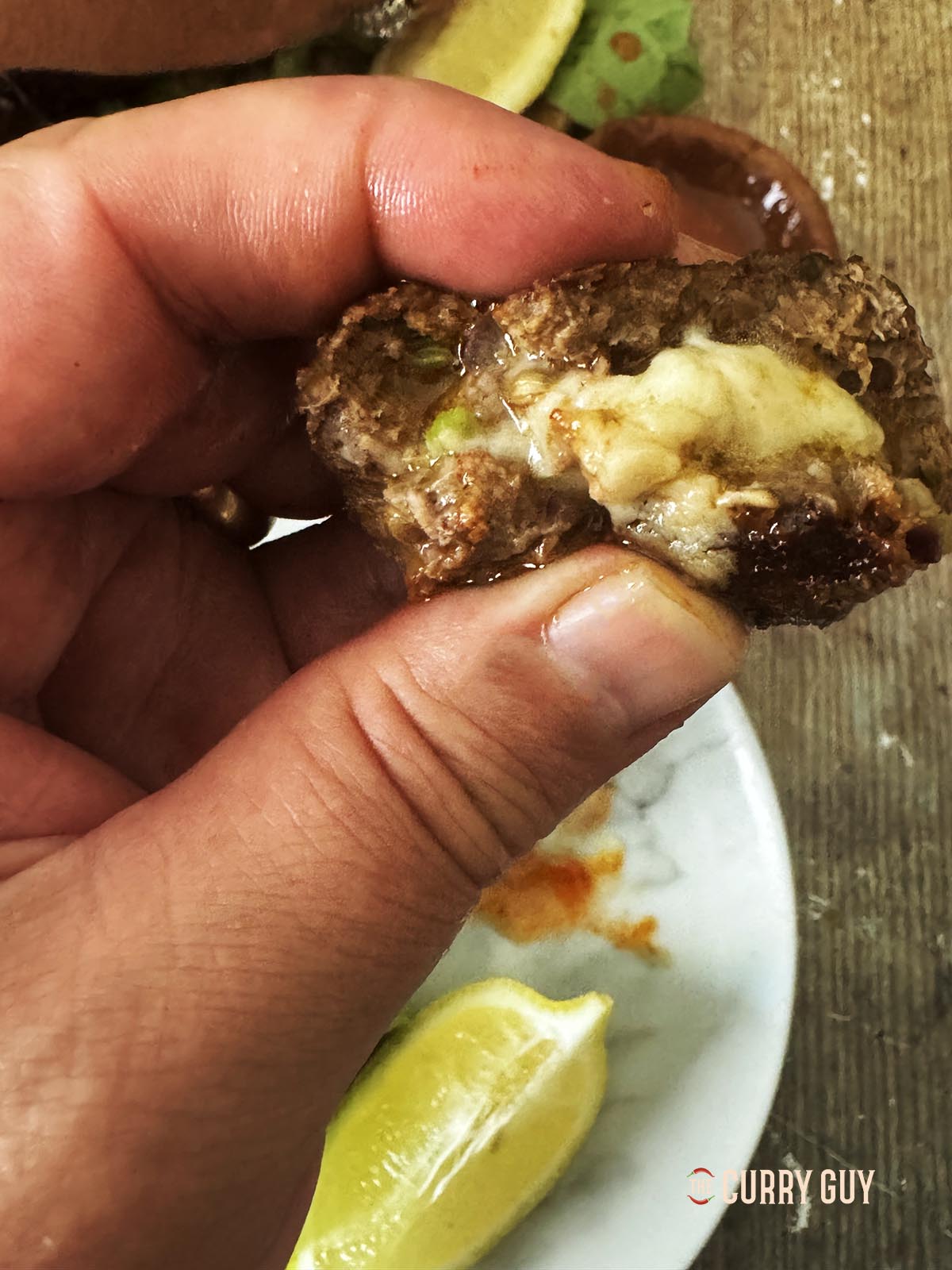 Squeezing a meatball to show the melted cheese.