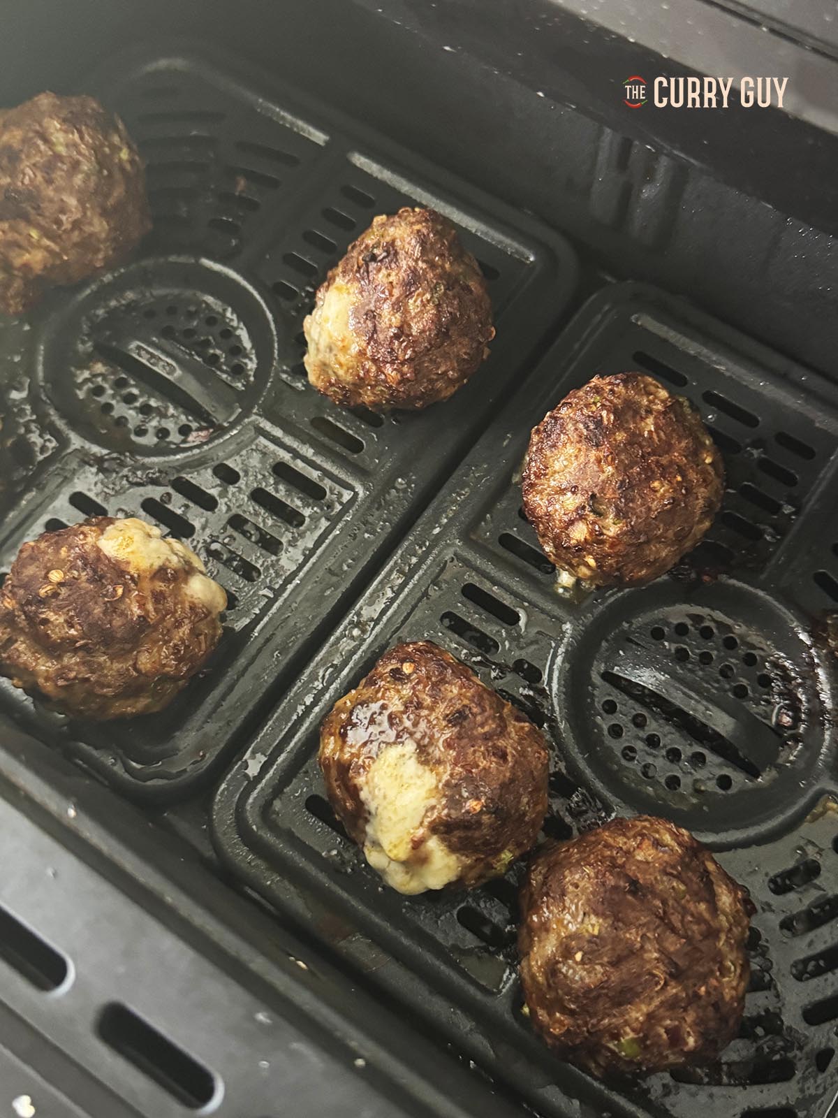 The cooked cheese stuffed meatballs in the air fryer basket.