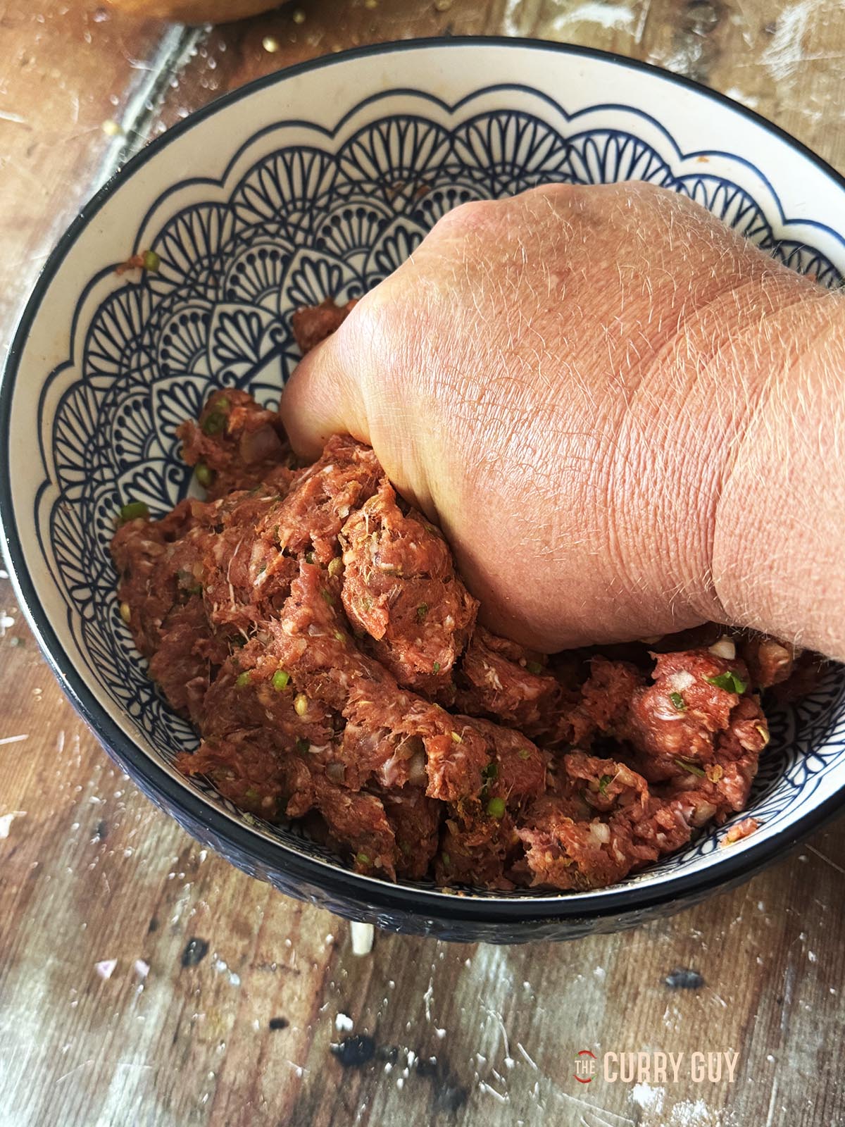 Kneading the meatball mixture until the meat is broken down and smooth.