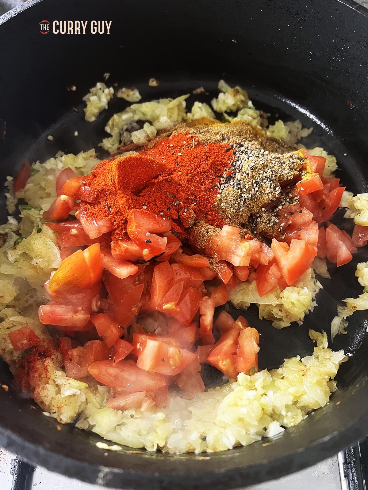 Adding the ground spices, tomatoes and stock to the pan.