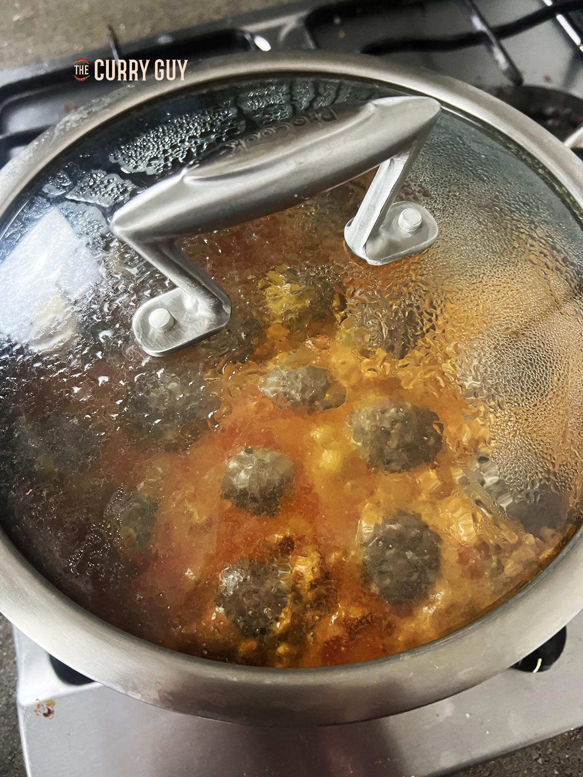 Cooking the beef koftas in a covered pan.