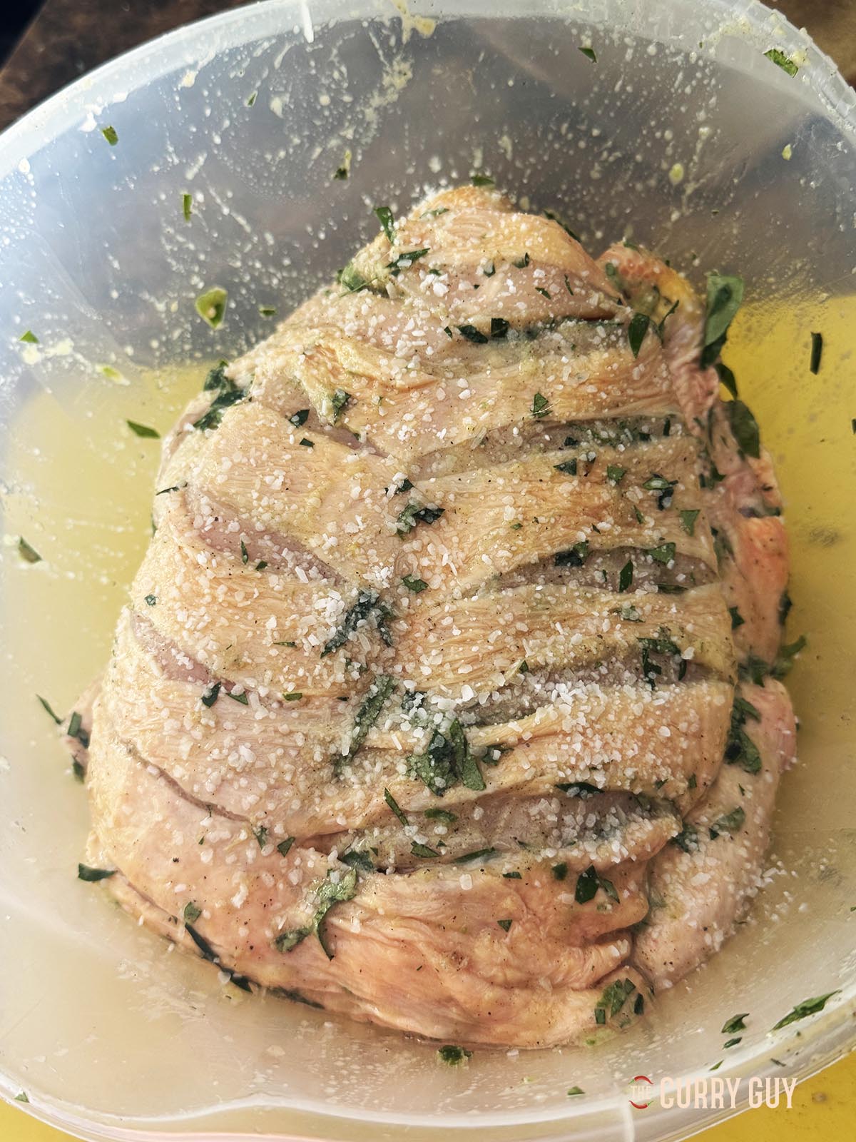 The chicken rubbed with the first marinade in a mixing bowl. 
