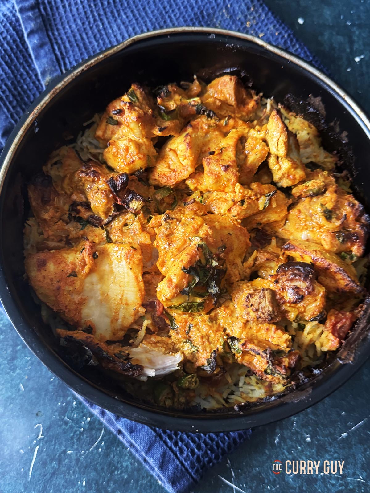 The browned chicken on top of the biryani.