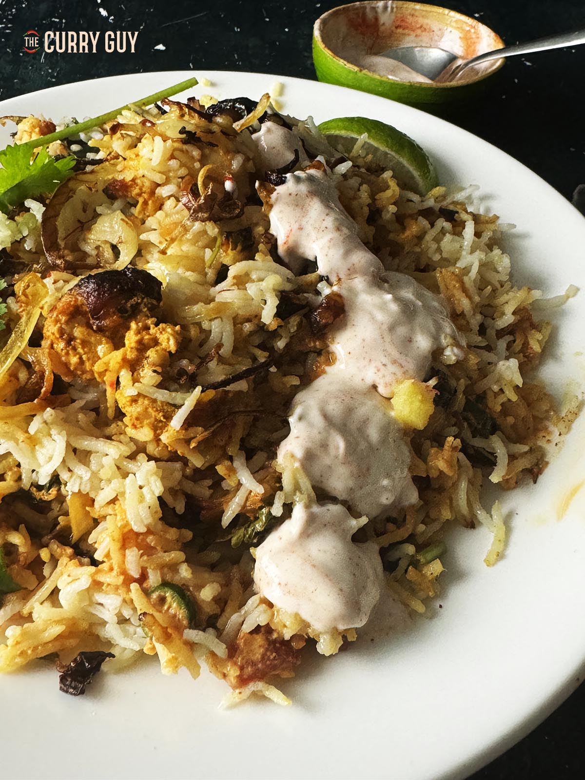 Transferring the chicken biryani in air fryer to a serving plate. Garnished with chilli raita and fried onions. 