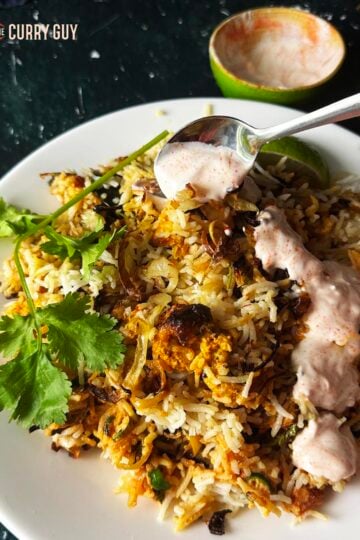 Air fryer chicken biryani plated up and drizzled with chilli raita.
