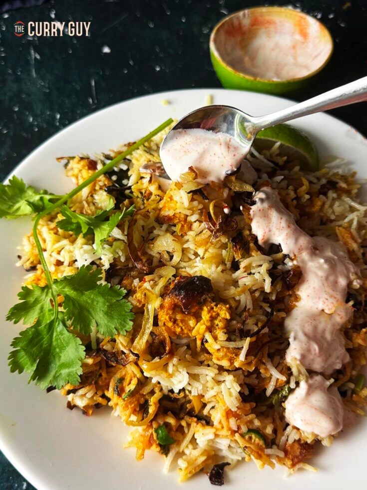 Air fryer chicken biryani plated up and drizzled with chilli raita.