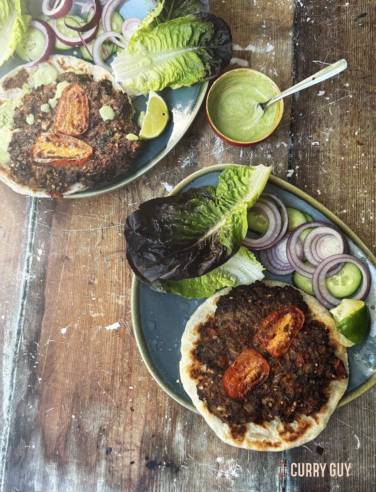 Chapli kebabs plated up with flat breads, vegetables and sauces.