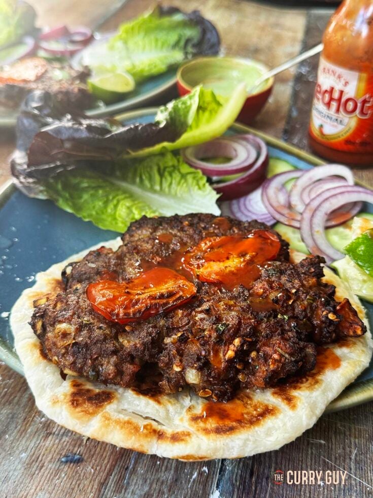 Chapli Kebab served on a flat bread with hot sauce and coriander chutney.