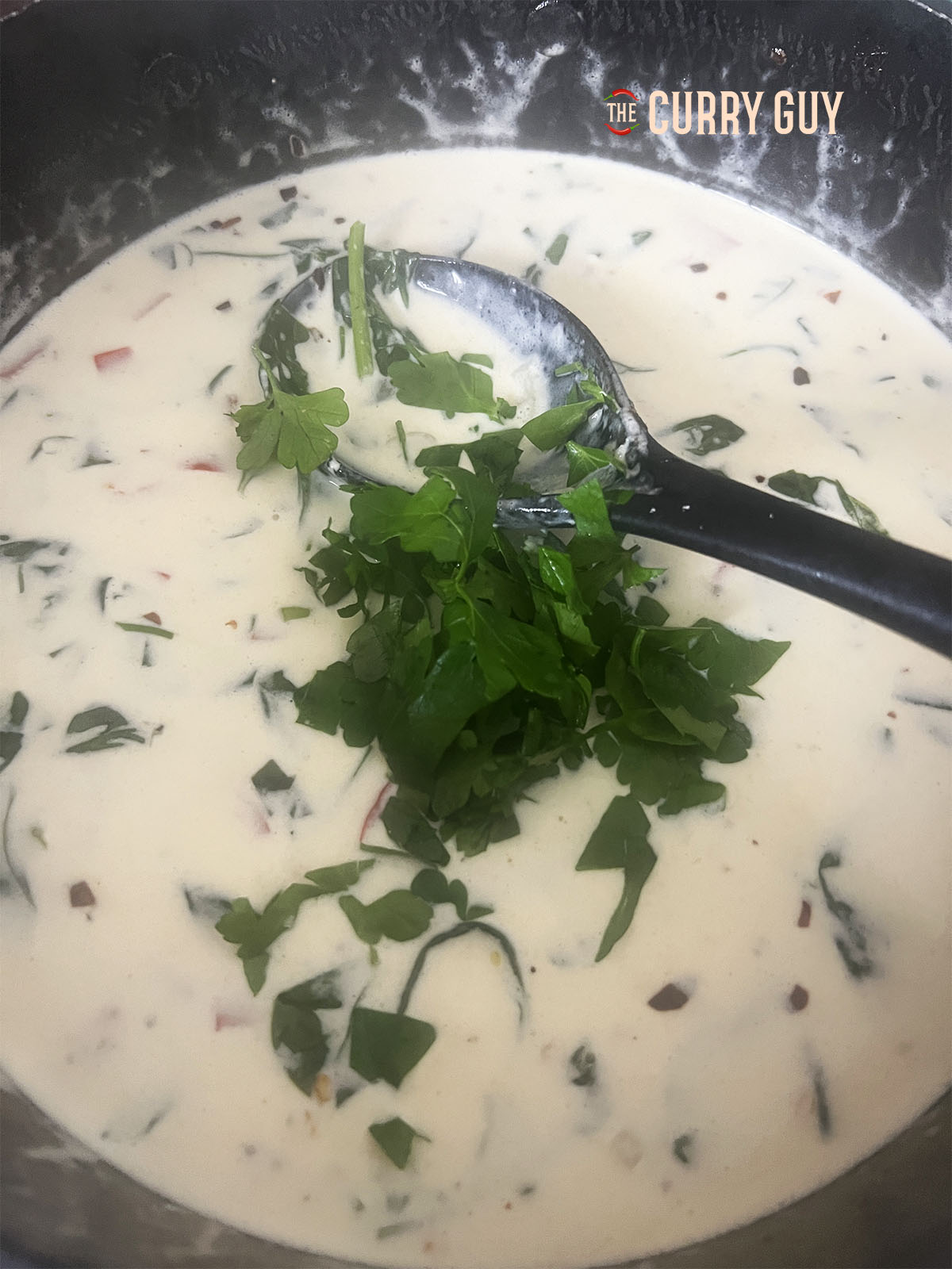 Parsley being added to the simmering sauce.