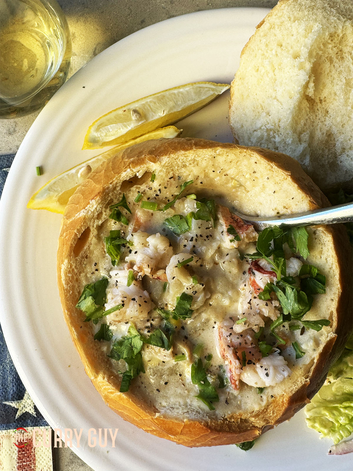 The clam chowder served with lobster tails and garnished with fresh herbs.