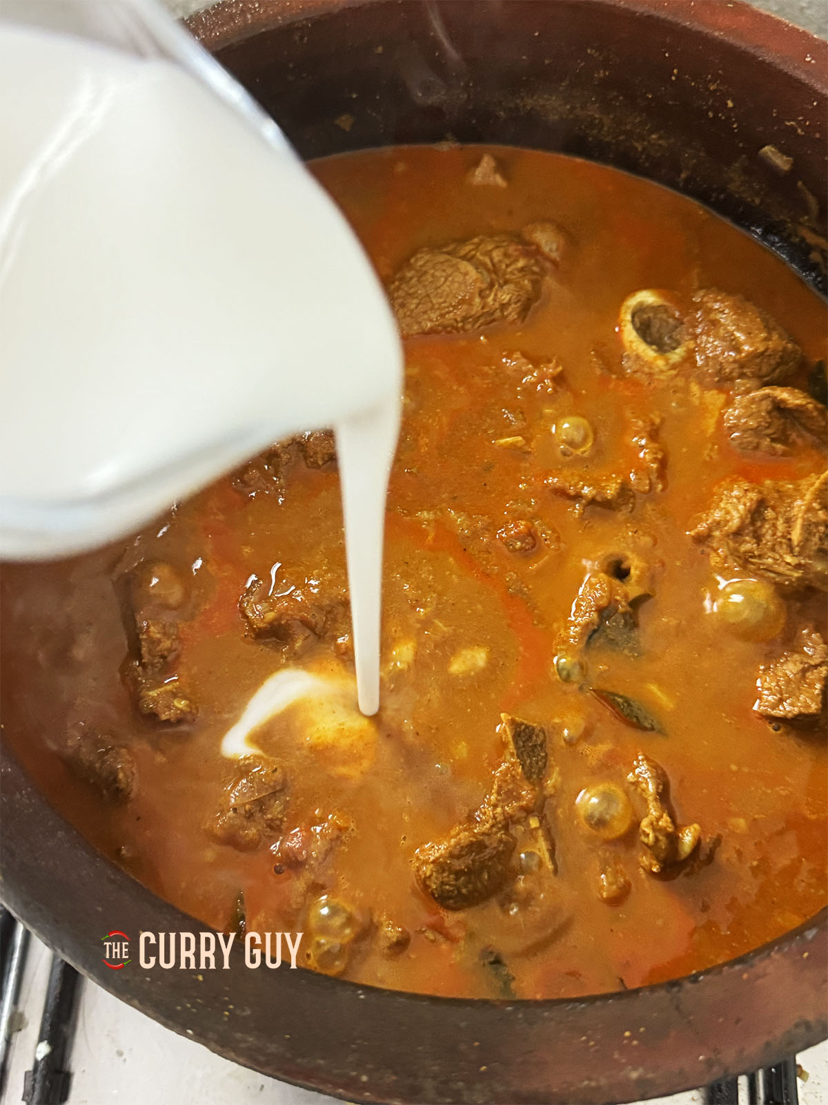 Adding the coconut milk to the curry.