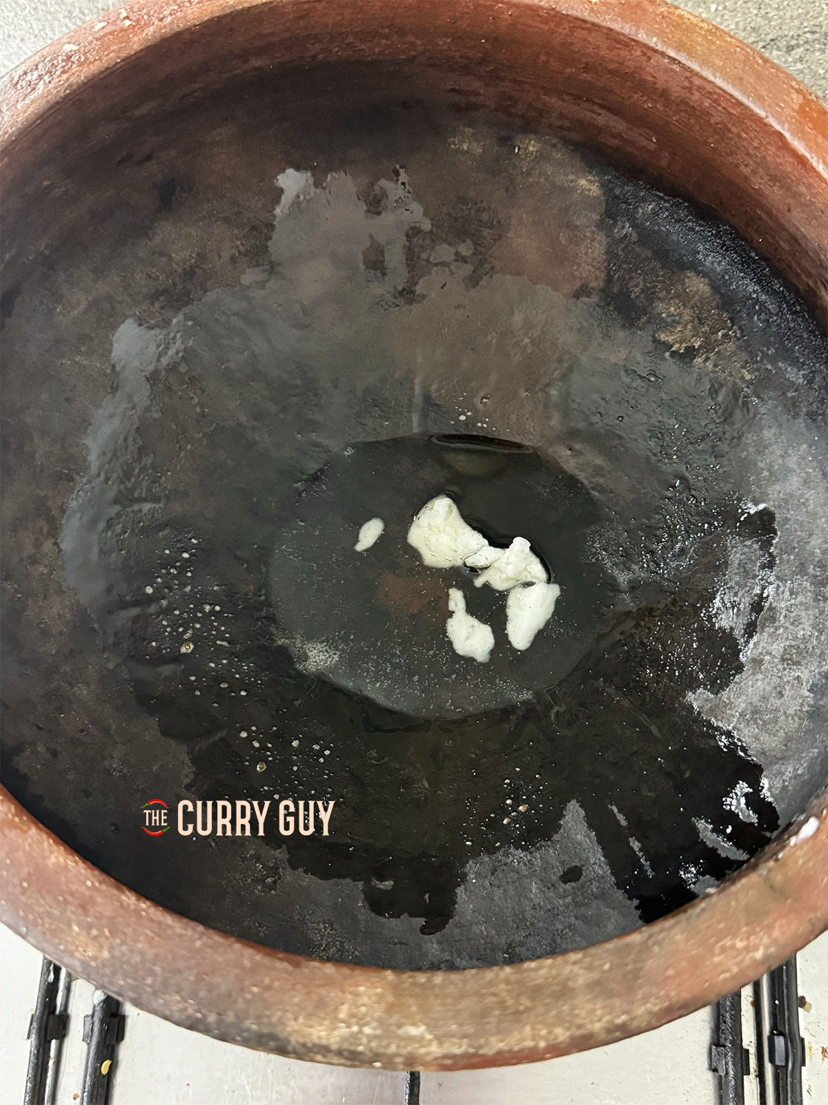Meltng coconut oil in a clay pot.