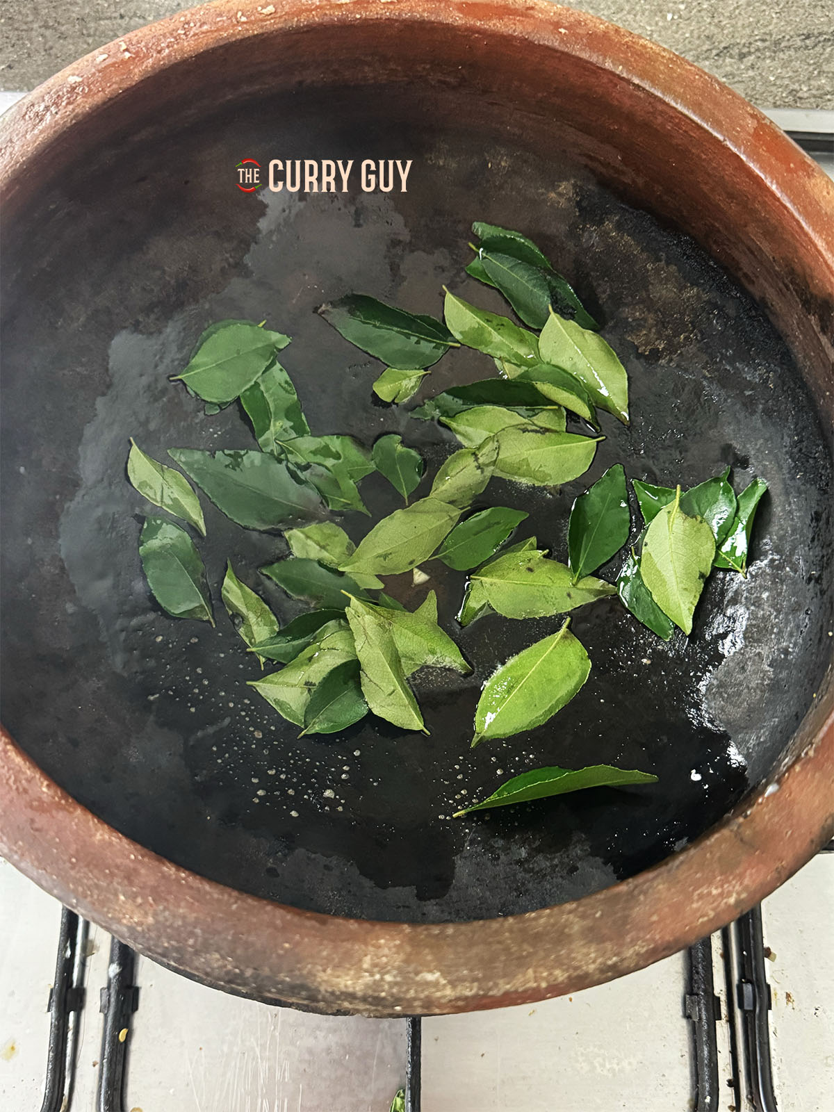Adding the curry leaves to the hot coconut oil.