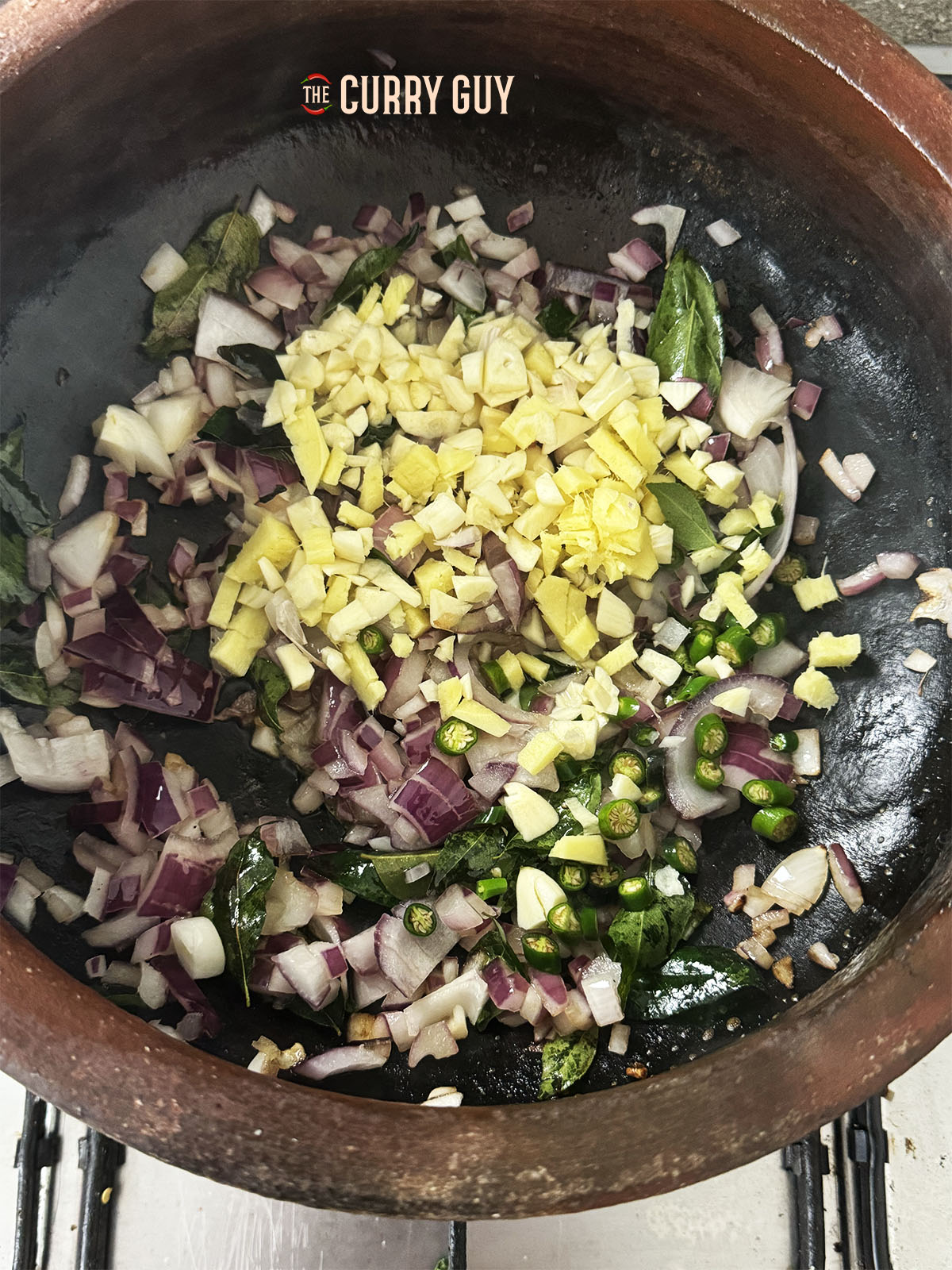 Adding the chopped garlic, ginger and chillies to the onion mixture in the pot.