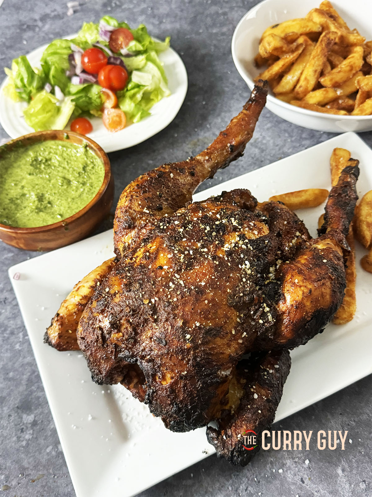 Puruvian Chicken - Pollo a la brasa, served at the table on a serving platter with side dishes.