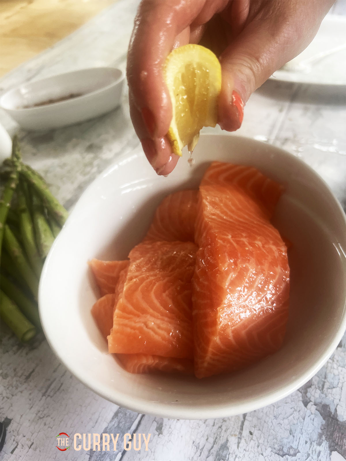 Squeezing the lemon over the salmon steaks.
